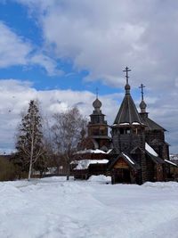 Church by building against sky during winter