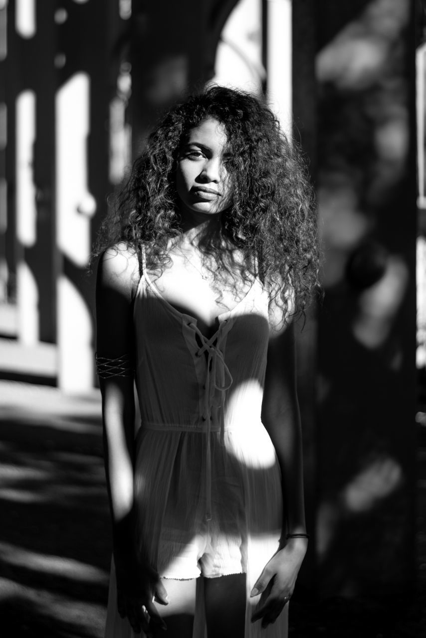 PORTRAIT OF BEAUTIFUL WOMAN STANDING AGAINST BLURRED BACKGROUND