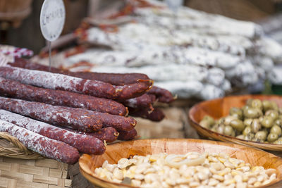 Stack of chorizo sausages and other delicacies for sale on a market stall.