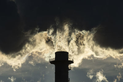 Smoke stacks pour pollution backlit by sunrise