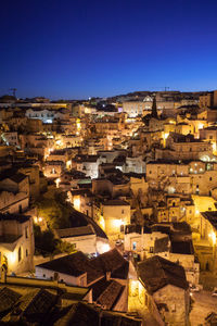 High angle view of illuminated buildings in city against clear blue sky