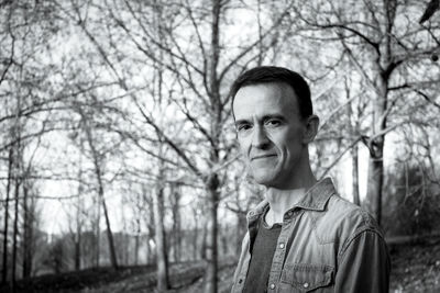 Portrait of young man standing against bare tree