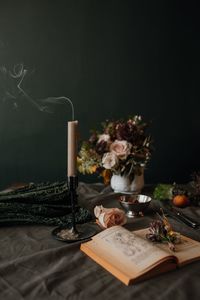 Close-up of book with flowers and candle on table