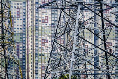 Low angle view of electricity pylons against buildings in city