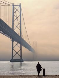 Low angle view of people on bridge against sky during sunset