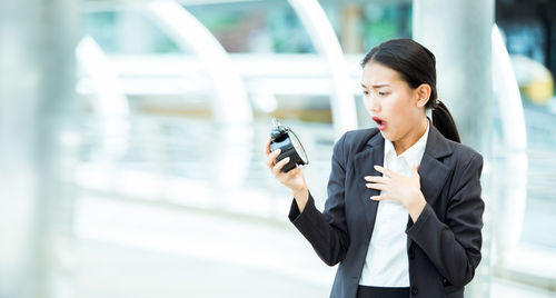 Shocked businesswoman holding alarm clock