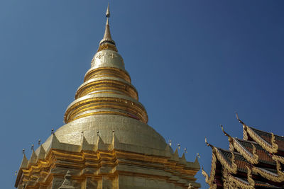 Low angle view of golden pagoda against blue sky