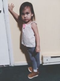 Portrait of cute girl standing against wall at home