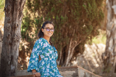 Young woman standing against trees