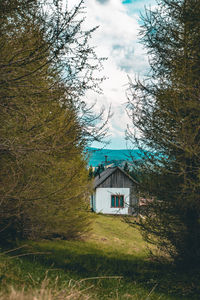 House on field by trees against sky