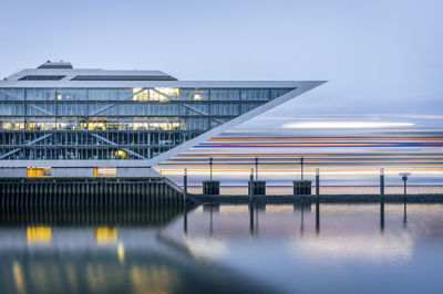 Germany, hamburg, long exposure of cruiseship passing dockland office building at dusk