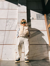 Low angle view of young woman standing against wall