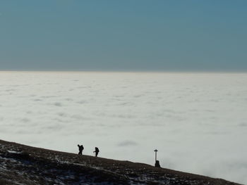 Men standing on shore against sky