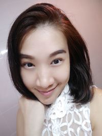 Close-up portrait of beautiful woman smiling while standing by wall