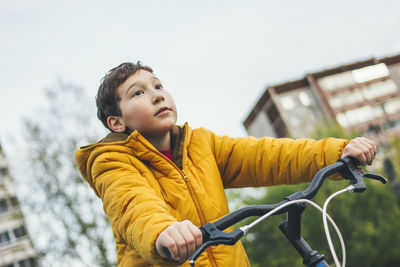 Boy cycling in car against sky