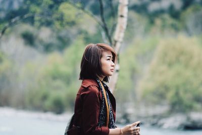 Side view of young woman looking away outdoors