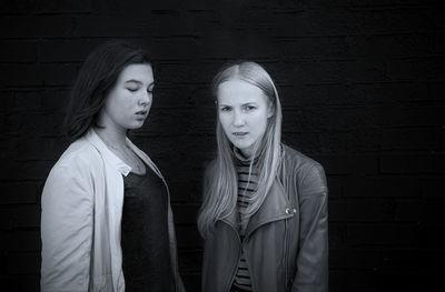 Portrait of teenage siblings standing against brick wall