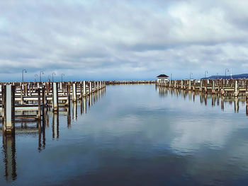 Wooden posts on pier over sea against sky