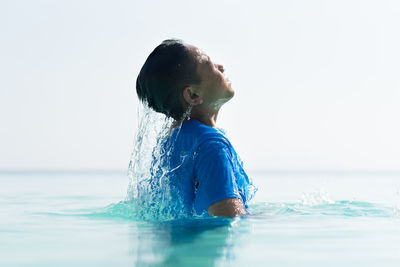 Side view of man swimming in sea against clear sky