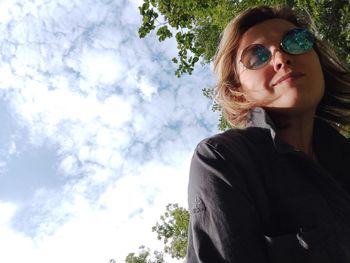 Portrait of young woman in sunglasses against sky