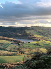 Scenic view of fields and a reservoir against sky