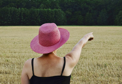 Rear view of woman wearing hat standing on field