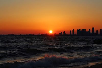 Scenic view of sea and buildings against sky during sunset