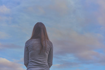 Rear view of woman standing against cloudy sky