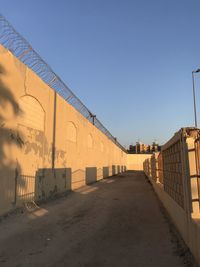 Footpath amidst buildings against clear blue sky