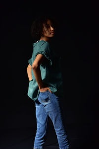 Side view of boy standing against black background