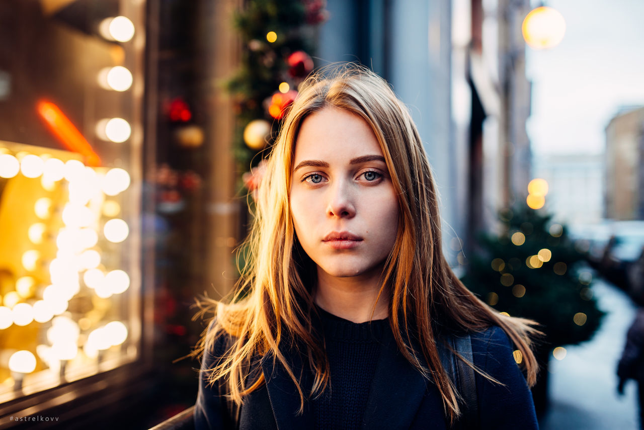 illuminated, young adult, focus on foreground, front view, night, one person, real people, headshot, young women, portrait, beautiful woman, blond hair, lifestyles, looking at camera, outdoors, close-up, one young woman only, city, people