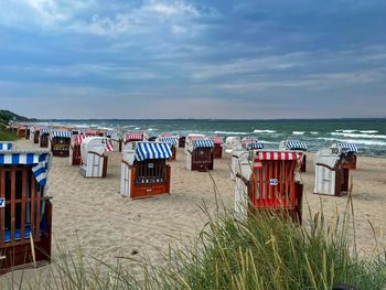 Hooded chairs on beach against sky