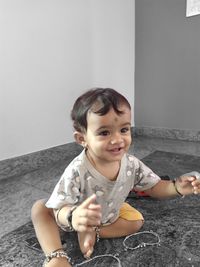 Portrait of cute girl sitting against wall