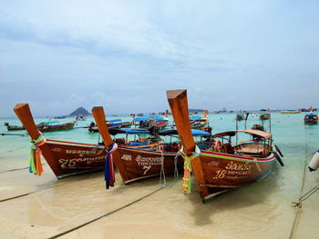 Fishing boats moored on beach against sky