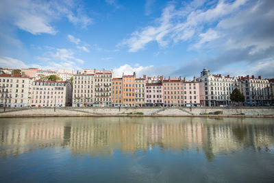 Buildings by river against sky in lyon city