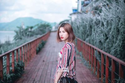 Portrait of woman standing on railing against mountain