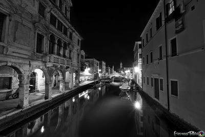 Canal amidst buildings in city at night