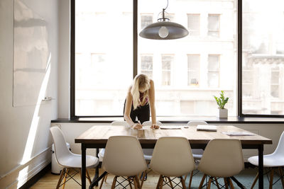 Businesswoman writing at desk in board room at creative office