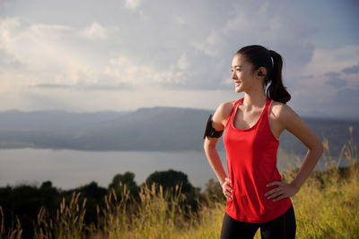 Young woman exercising on mountain against cloudy sky during sunset