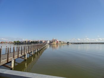 Scenic view of river by buildings against blue sky