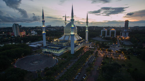High angle view of city lit up against cloudy sky