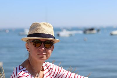 Portrait of serious woman wearing hat with sea background
