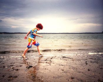 Side view of boy walking at beach