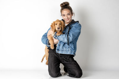 Portrait of young woman with dog against white background