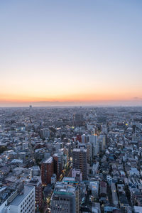 High angle view of city buildings against clear sky during sunset