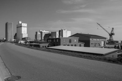 Road by buildings in city against sky