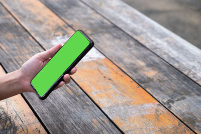 Close-up of hand holding mobile phone on table