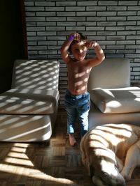 Portrait of shirtless boy sitting on seat at home