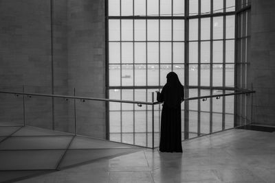 Rear view of woman standing by window in building