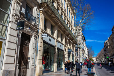 People walking on street amidst buildings in city